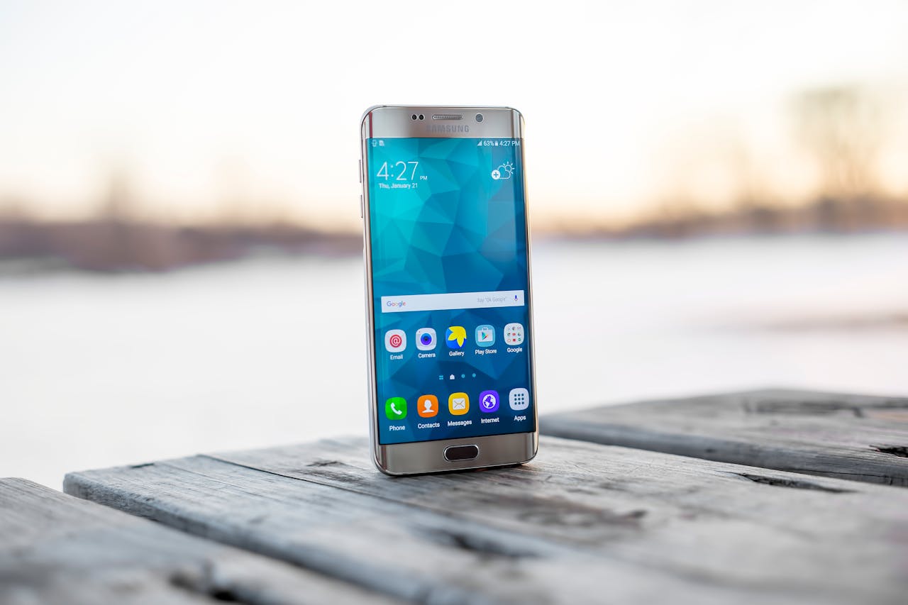 Samsung smartphone placed on a wooden surface outdoors during sunset.